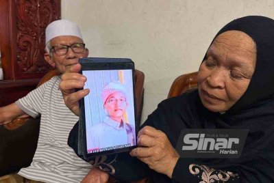 Ruhani (kanan) dan suaminya, Wan Abdul Rahman Wan Yaacob, 79, (kiri) menunjukkan gambar arwah Wan Ahmad Faris yang tinggal sebagai kenangan buat mereka.