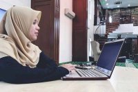 Siti Nurazlinee menulis kandungan laman sesawang serta pengurusan media sosial dari rumah.