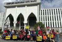 Orang Asli berkumpul sambil memegang sepanduk di pekarangan kompleks Mahkamah Kota Bharu pada Isnin.