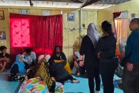 Seorang tahanan wanita dibawa ke rumah keluarganya untuk melawat jenazah suaminya buat kali terakhir di Kampung Sundang, di sini, pada Isnin.